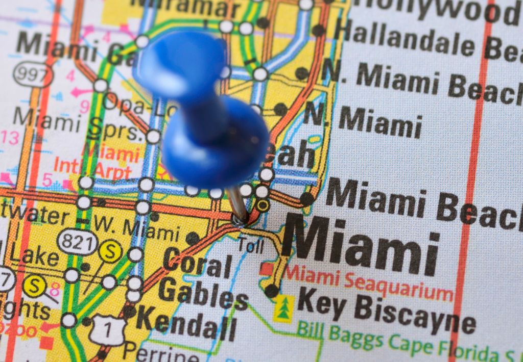 This is an image of a miami map with a blue pin in it denoting a target neighborhood for real estate investment. Coral gables and key biscayne are also seen featured in this map.