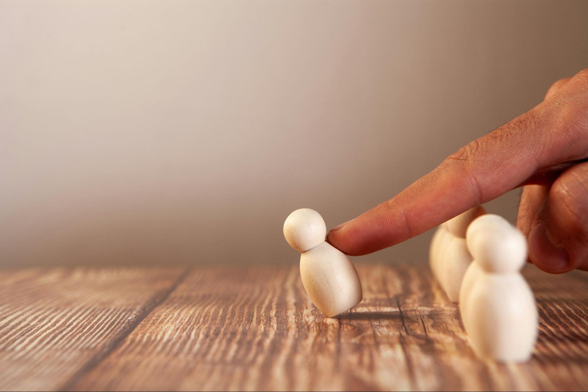 a finger pushes over a pawn which illustrates how volnurable investors are when they invest in a real estate investment trust.